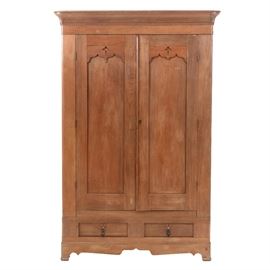 1860s Gothic Revival Walnut Armoire: A 19th century, Gothic Revival walnut armoire. This armoire has a cornice with beaded border accent, two doors with half-acorn mounts and bellflower cut-outs, two doors with key escutcheon and a cabinet base with two drawers having embossed, brass-tone hardware and black wood finial pulls. Circa 1860s.