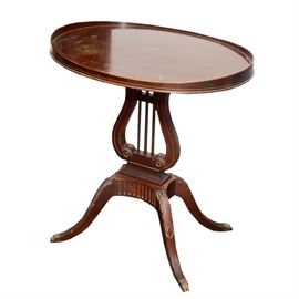 Phyfe Style Lyre Pedestal Side Table by Mersman: A Duncan Phyfe style lyre side table by J. B. Mersman. This mahogany table has an oval top with border, which is raised at the sides. It has a lyre pedestal raised on splayed, cabriole legs with fluted detail between them. The legs have acanthus carving on the knees and brass paw caps on the feet. The underside of the table is marked, “Mersman.”