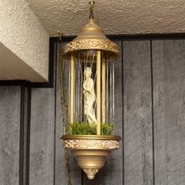 Vintage Oil "Rain" Classical Goddess Lamp: A vintage oil “Rain” Classical goddess lamp . The light has a central figure of a classical molded plastic sculpture of a woman standing among ferns within a colonnade. She is surrounded by thin strands through which oil spins when the lamp is turned on, to make the appearance of rain. The lamp has a long chain for hanging.
