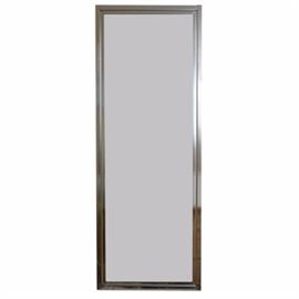 Metal Framed Wall Mirror: A metal framed wall mirror. This piece is a full-length mirror framed in a silver toned metal frame designed to be hung on a wall.