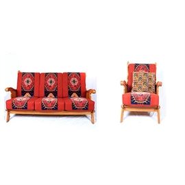 Tapestry Upholstered Arm Chair and Love Seat: A tapestry covered love seat and matching arm chair. These two pieces feature a gold oak frame with open slats, ornate and detailed carved sides, handles, and legs. The cushions of the love seat and arm chair are upholstered in a bright coral fabric accented with tapestry detail The tapestry upholstery features a color palette of royal blue, orange, green, red, cream, brown, and green.