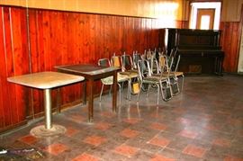 Green and yellow padded chrome chairs, square tables and player piano (missing player parts).