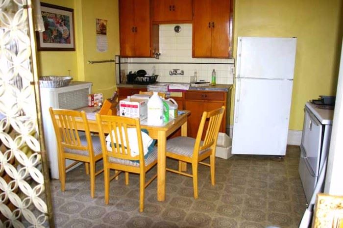 Kitchen table, chairs, refrigerator, stove, sink, cabinets, kitchen supplies.