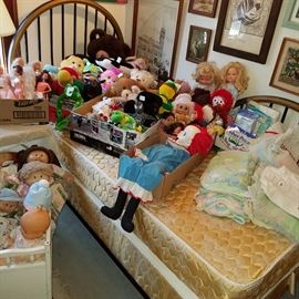 Stuffed animals and dolls on twin bed (footboard detached and against the wall to the right)