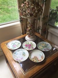 Vintage porcelain floral vase and porcelain china plates on top of square side table with glass top