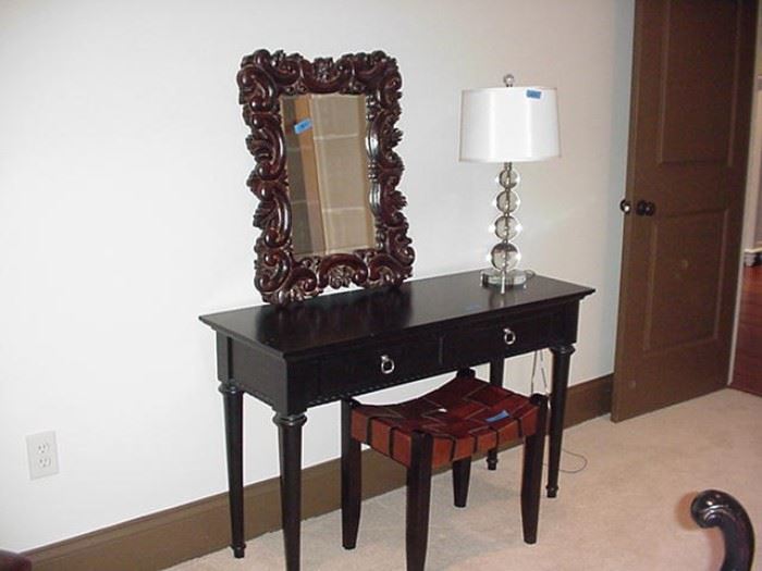 Two-drawer dressing table; woven leather stool; glass sphere and Lucite lamp; carved wood frame with beveled mirror