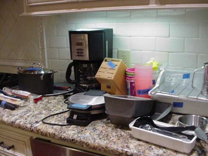 Small appliances including Krups coffee maker; Cuisinart waffle maker; plastic pans; utensils; pots; knife block by Henckels; baking pans; and more