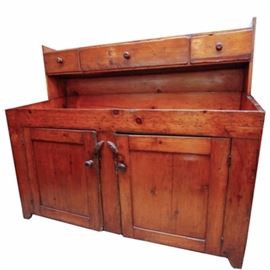 Antique Southern Pine Dry Sink: An antique southern pine dry sink. This solid pine piece features a shelf above three aligned drawers with knob handles with a solid backsplash. The dry sink base features a rectangular top over two recessed panel cabinet doors with knob handles and turn locks opening to a shelf and terminating on bracket feet. There are no visible maker’s marks.