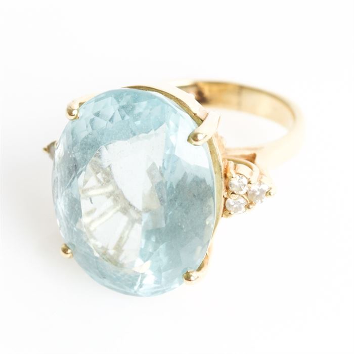 14K Yellow Gold, 17.65 CTS Aquamarine, and Diamond Cocktail Ring: A 14K yellow gold cocktail ring featuring one center 17.65 cts faceted oval cut aquamarine flanked by round brilliant cut diamond side stones.