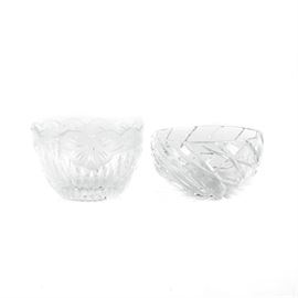 Pair of Glass Bowls: A pair of glass bowls. This includes a bowl with diagonal cross patterns with a starburst to the underside. Another bowl has scalloped edges with floral designs along with cut designs to the base.