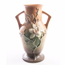 Vintage Roseville Pottery "Magnolia" Double Handled Vase: A large Roseville Pottery Magnolia terra cotta vase. Featured is an urn style vase with two curved handles and a large molded depiction of magnolia blossoms. Rendered in tones of terra cotta, white and green, this vase is embossed marked to the verso “Roseville/U.S.A./98-15”" with a notation in black, “14F”.