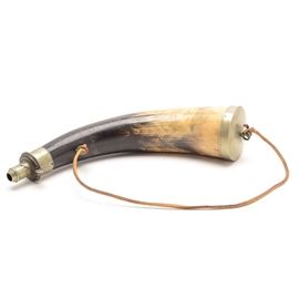 Antique Powder Horn: A circa mid-19th-century British gunpowder horn, made from a steer’s horn with brass end caps. The cap at the narrow end opens by pushing a button, which is “spring loaded” using a circular band of flexible metal, and snaps closed when released. There is a leather carrying thong which is likely non-original. Marked to the cap “James Dixon & Sons, Sheffield”.