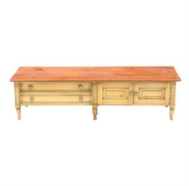Vintage Louis XVI Style Credenza or Coffee Table: A circa mid-century Louis XVI style credenza or coffee table, in pine. This long, low piece has a yellow finish to the base, with two drawers to the left and a cabinet with double doors to the right. The drawers and doors have porcelain knobs with designs of European figures in period ddress. The piece stands on vase turned feet.
