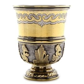 Tane Mexican Gold Wash Sterling Silver Footed Chalice: A Mexican sterling silver footed chalice by Tane. The two-tone chalice features a gold wash to interior and exterior, having hand chased detailing with stippled accents and raised Aztec style motifs to the base. The chalice is marked “Sterling 925 Hecho En Mexico 90M Tane” to the base. The total approximate weight is 10.390 ozt.