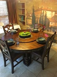 Large dark wood round top dining table with lazy Suzy serving top and 6 matching chairs from Neberaska Furniture Mart.  The table is one price while the chairs are priced as a set of 6.  