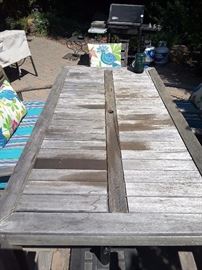 7.5 foot long outdoor wood picnic table, it has a split so this item needs to be refinished, fixed. There is a hold for an umbrella. New seated cushions and chairs. From World Market.