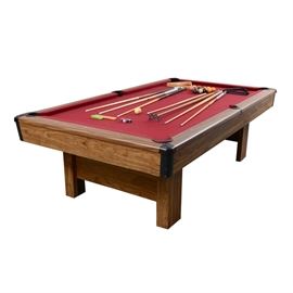 Windsor Slate Billiard Table and Accessories: A Windsor slate billiard table and accessories. This traditional pool table features a Windsor red felt playing field, an oak laminate top rail with imitation mother-of-pearl inlay sights, and black acrylic pockets, being raised on square columnar legs. The table comes complete with pool balls, six pool cues, a bridge stick, two triangles and a wall mounted storage rack. The pool table is marked “4 × 8 Slate Windsor” with labels to the base.