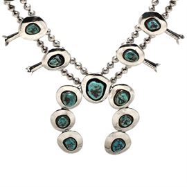 Sterling Silver Turquoise Squash Blossom Necklace: A sterling silver turquoise squash blossom necklace. The hand-crafted necklace is by an anonymous artist and features bezel set freeform turquoise cabochon stones with hollow sterling beads and sterling squash blossom bead accents.