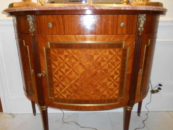 Foyer:  The curved Italian demi-lune commode with different wood (walnut/rosewood)  marquetry and ormolu has one upper drawer and three lower doors.  It measures 46" wide x 19" deep x 38"" tall.  Included are three keys, which will be with the cashier. 