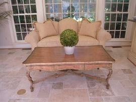 Sun Room-Atrium:  The elegant three-cushion tight back sofa has a single seat cushion and rolled arms.  It measures 83" wide and was made by CAMERON COLLECTION.  A view of the unique back is coming up.  In the foreground is a one drawer table that measures 54" wide x 30" deep x 21" tall.  The boxwood topiary is faux.