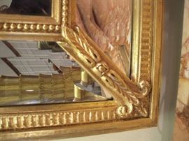 Foyer:  A corner of the mirror (32" x 46") which is above the demi-lune commode shows the detailed gold outer frame and the inner mirror panel frame.     