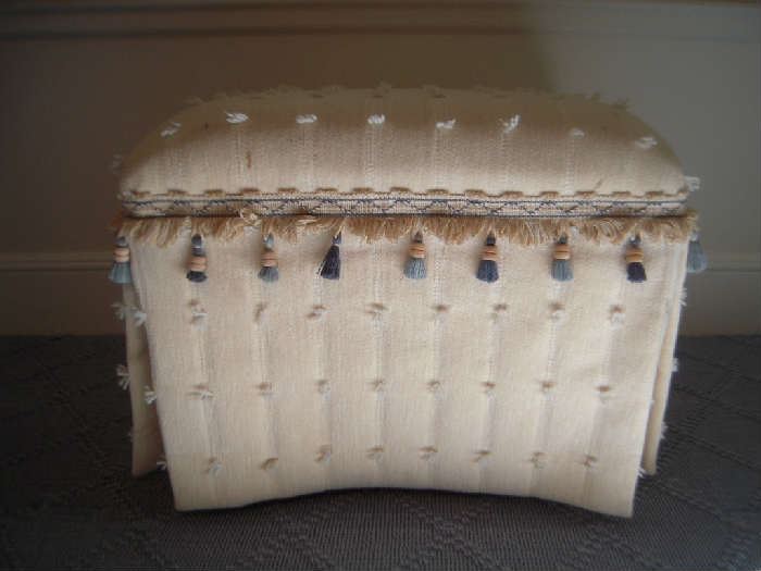 Bedroom #1-Upstairs:  A cream color ottoman has blue and taupe tassel fringe. 