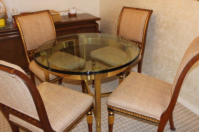 Glass and heavy brass table and four elegant dining chairs.