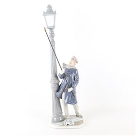 Lladro "Lamplighter" Porcelain Figurine: A Lladro porcelain “Lamplighter” figurine. The tall figurine depicts a lamplighter from bygone times lighting a street lamp with a long removable torch in the iconic LLadro tones of blue, white, gray and brown. The figurine is marked to the underside Lladro Hand Made in Spain Daisa 1981 5205.