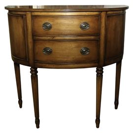 Maple Demilune Foyer Table: A maple demilune foyer table. The table features oval Hepplewhite style pulls to the center two drawers flanked by spring release side doors. The table rests on turned and reeded legs. The table is unmarked.
