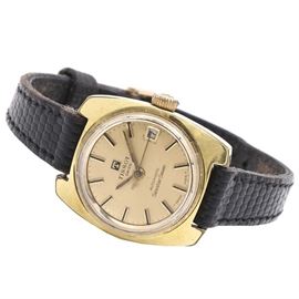 Tissot Swiss Automatic Seastar Seven Wristwatch: A Tissot Swiss Automatic Searstar Seven wristwatch. This piece features a rounded, rectangular stainless steel waterproof case with a yellow tone plated bezel. It houses a round, satin yellow tone dial, with yellow tone dash indexes and hands, and a sunken date window at three o’clock. Attached, is a thin, black snake patterned leather strap.