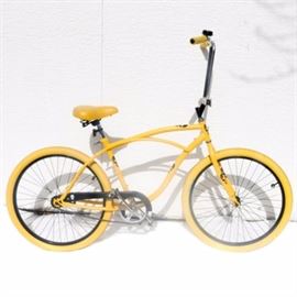Men's Yellow Spider Bike: A men’s yellow spider bike. This metal bike features an all over yellow appearance accented with black skulls and an Electra bell with the image of a skull. No manufacturer markings are present to the bike.