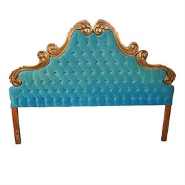 Vintage Velvet Button-Tufted Headboard: A vintage mid-twentieth century headboard. The king-size headboard features ornate gilded and carved wood scrolls along the arched top. The center of the headboard is padded and covered in turquoise colored velvet with button tufting throughout. The legs are square and straight and made of stained wood. No maker’s marks.