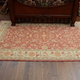 Hand Woven Wool Rug: A hand woven wool rug with a floral motif center on a field of light salmon, wide border with a continued floral design.