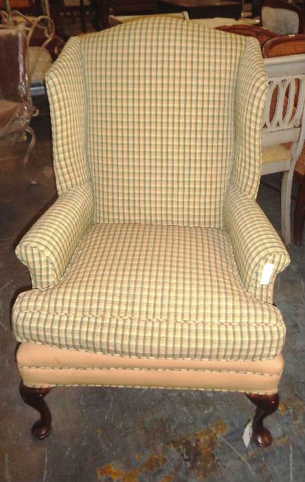 Comfortable yellow plaid wing chair with wooden legs.