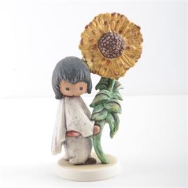 "The Children of DeGrazia" Goebel Figurines: A pair of porcelain figurines from The Children of DeGrazia collection produced by Goebel. This pair offers The Sunflower and a figurine of a girl carrying a basket of flowers, aside a sign reading “DeGrazia Figurine Collection Goebel W. Germany”.