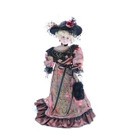 Paradise Galleries Porcelain Doll "Katerina": A Paradise Galleries Porcelain Doll, “Katerina.” Katerina’s style of dress is from the Mid 19th Century Victorian Gone with the Wind Era. She wears a red satin dress with lace and embroidered embellishments. She dons a black hat with a center rose and black lace. Katerina is part of the Ladies of Aristocracy series and has an included booklet.