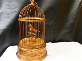 Music box in the shape of a birdcage:German 1900-1920 Brass Cage contains a feathered mechanical bird. The base of the birdcage contains a mechanical music device to give the appearance of the bird singing