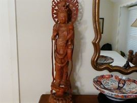 carved wooden figurine of the goddess of  Mercy  figure stands on a floating lotus blossom holds a vase of flowers in her left hand and a mandela is shown behind her head  Quality of carving is of very high caliber.