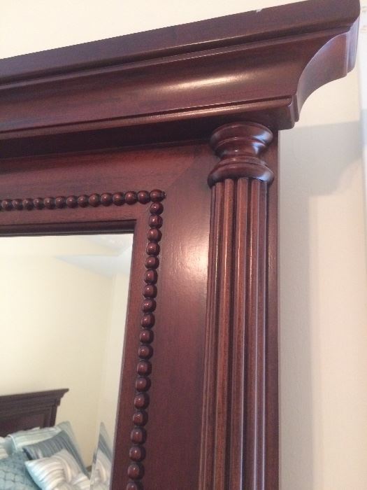 close up of detailing on corner of cherry mirror with six drawer dresser