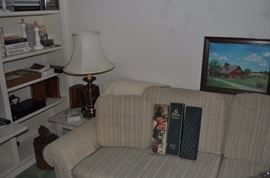 Books, candlesticks, small white wooden table, Stifel vintage lamp, sofa with matching love seat, vintage glove boxes, framed barn oil painting