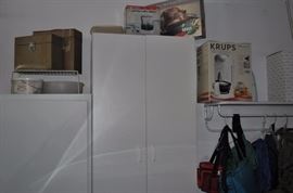 White storage cabinets, Krups coffee maker, assorted backpacks, hiking gear, ice hiking pick, Gevalia coffee maker