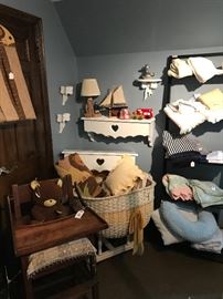 The babies area  with antique crib and antique highchair along with receiving blankets and other assessories 