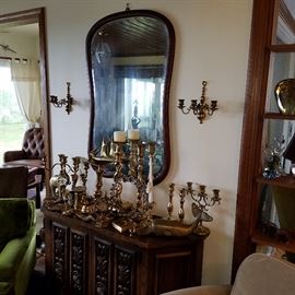 Credenza displaying brass items.  Shaped beveled mirror in oak frame above