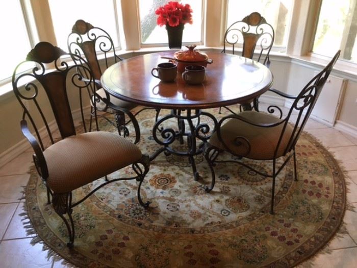 Wood, wrought iron dining set with 4 upholstered seat arm chairs, also round rug with fringe