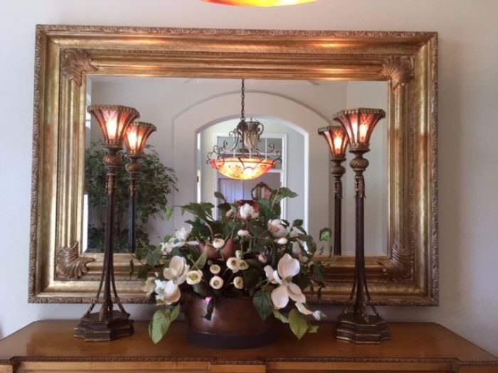 Large gilt wall mirror with fleur-de-lis detail, also large potted silk magnolia decor and pair of metal table torchieres. UPDATE: Large mirror SOLD Saturday; rest available.