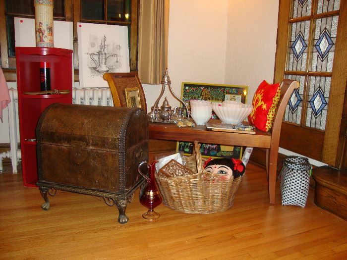 Contemporary trunk, paper mache mask of a Chinese woman, Turkish coffee set, Anchor Hocking Rachel fruit bowl set, pencil drawings from Saudi Arabia, Chinese red painted corner bookcase