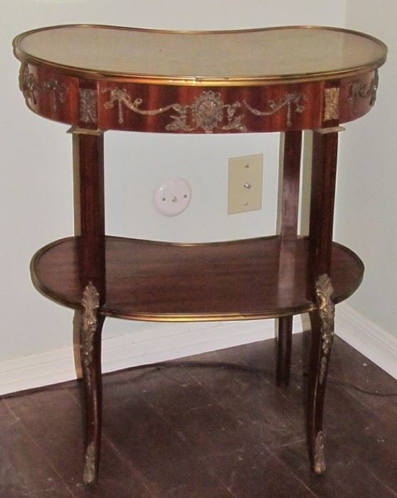 19th Century French Kingwood ormolu mounted kidney shaped side table with a center lower tier. The  parquetry top and lower tier is enclosed in a cast bezel.  The center of the apron has an escutcheon with a wonderful detailed foliate. There are similar mouldings  on the sides. The table stands on thin, elegant cabriole legs. The knees have a very elaborate Rococo casting with acanthus leaves and flowers with continue beading down the front and finish in very elegant sabots. 