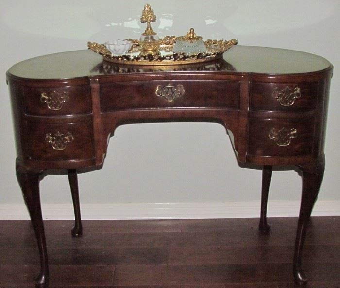 Vintage Henredon Furniture Kidney Shaped Queen Anne Style Dressing Table/Desk in mahogany. The legs are hand carved cabriole legs with a carved shell  on the "knee" of each leg. (42"W x 22"D x 30.5") Shown with A Gold Plated Vintage Mirrored Vanity Tray (20.5" x 14") , Perfume Botle and Cherub Top Crystal vanity Hair Receiver/Potpourri Dish and Haviland Limoges Ring Holder 