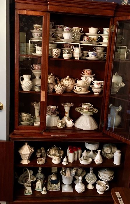Tall solid wood china cabinet filled with glassware and china collections.