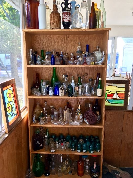 Part of the bottle collection surrounded by stained glass pictures.